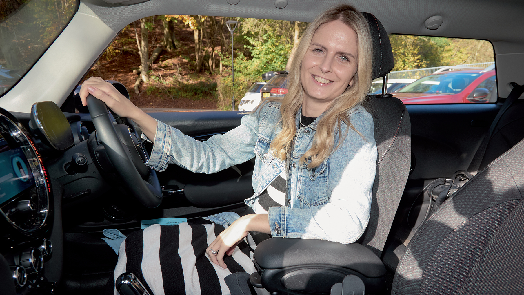 Emma smiling in her Motability Scheme car wearing a dress and a jacket.jpg