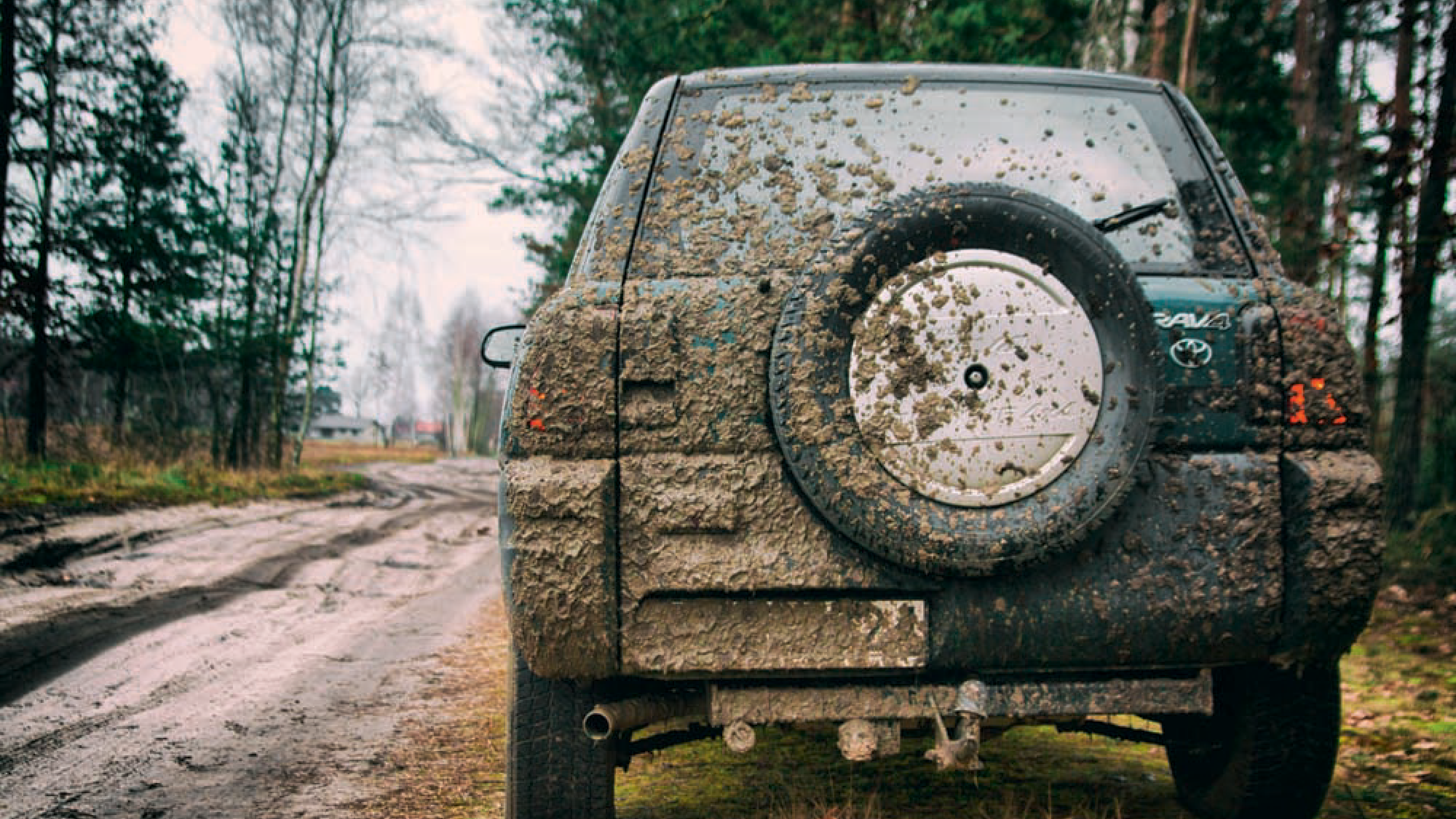 a-muddy-car-parked-next-to-a-muddy-country-lane.png