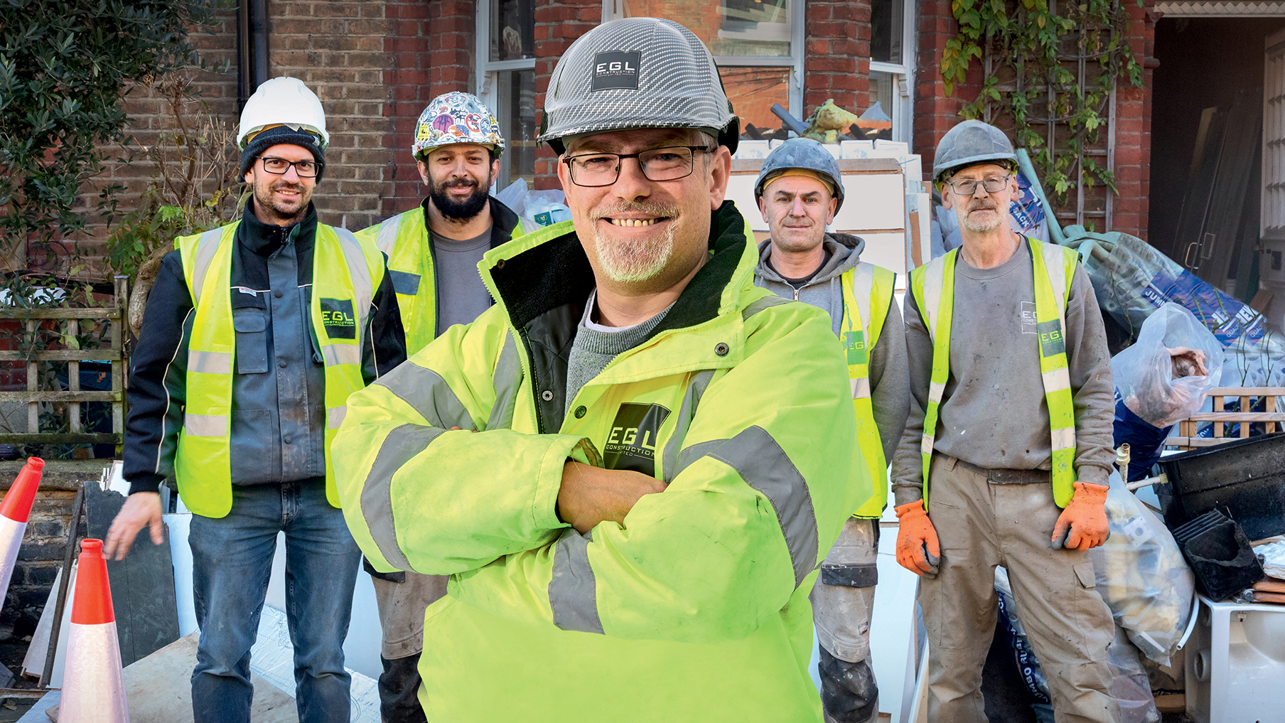 5 deaf builders wearing their helmets and yellow jackets and smiling 