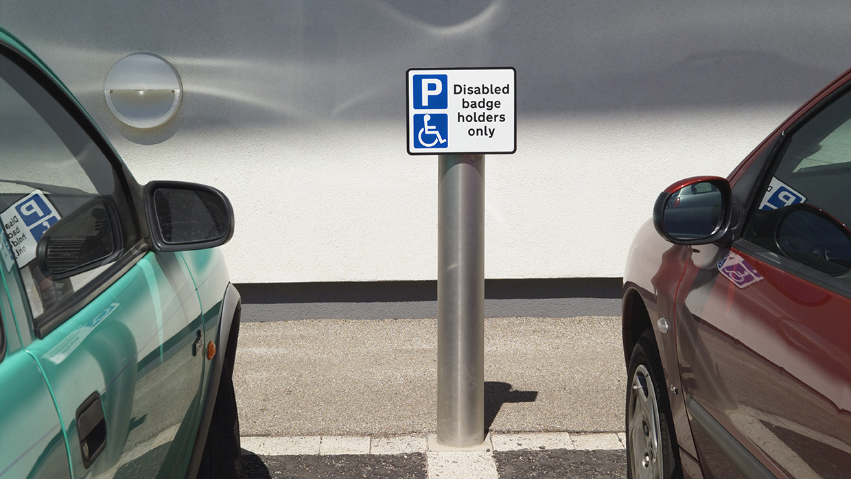 Two cars parked either side of a Disable Blue Badge Holders Only sign
