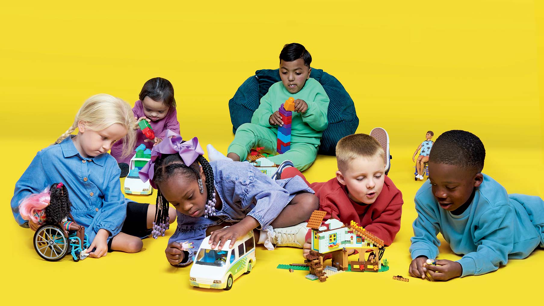 Six children (disabled and non-disabled) playing with toys in front of a yellow background
