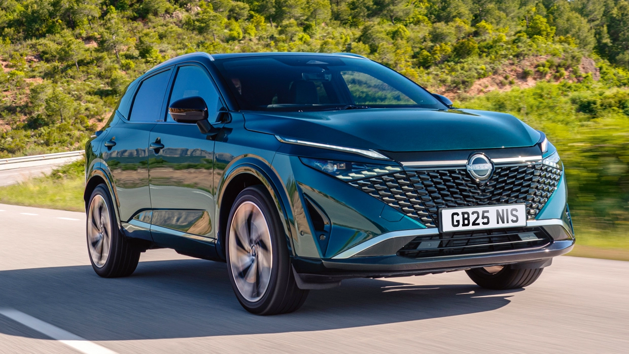 A teal Nissan Qashqai driving on a country road in sunny conditions