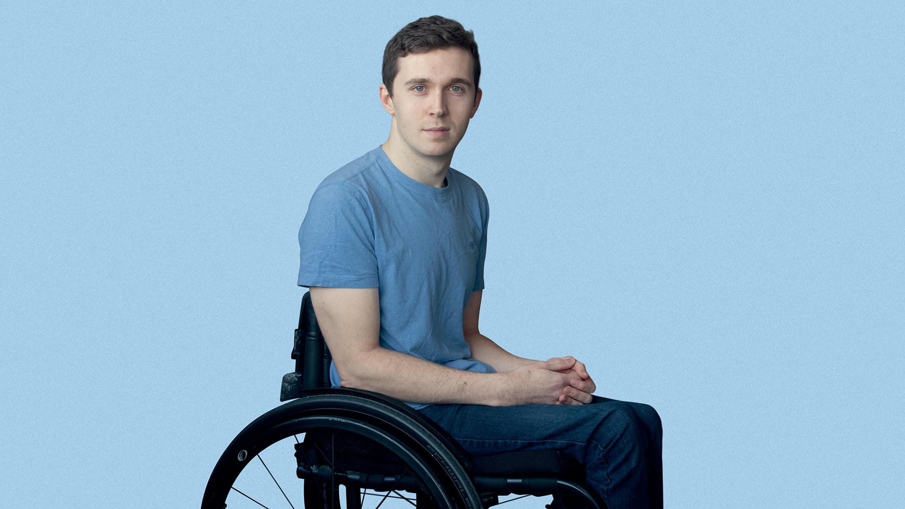 Ed Larkin sat in his wheelchair wearing a blue t-shirt in front of a blue background
