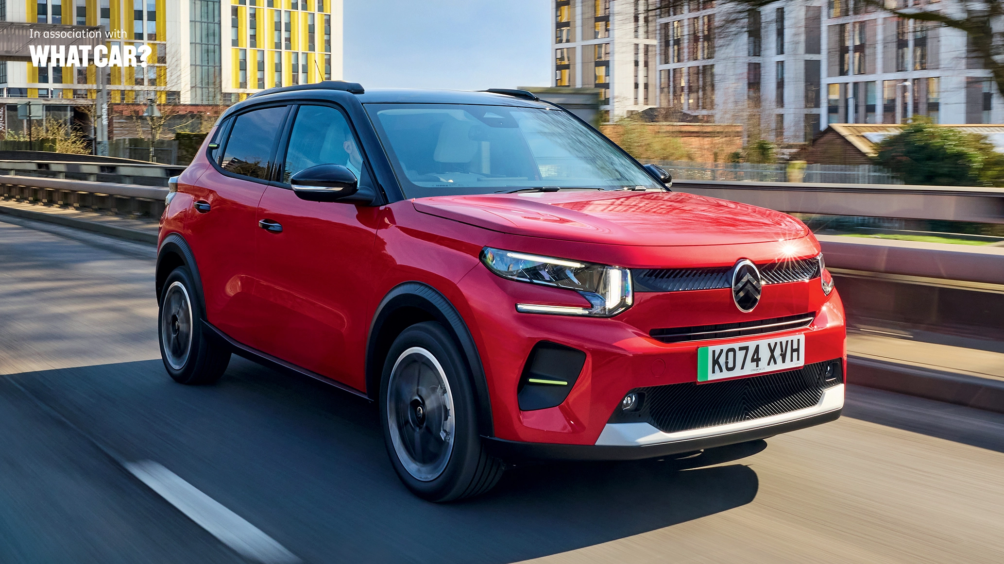 A Citroen E-C3 driving in an urban landscape