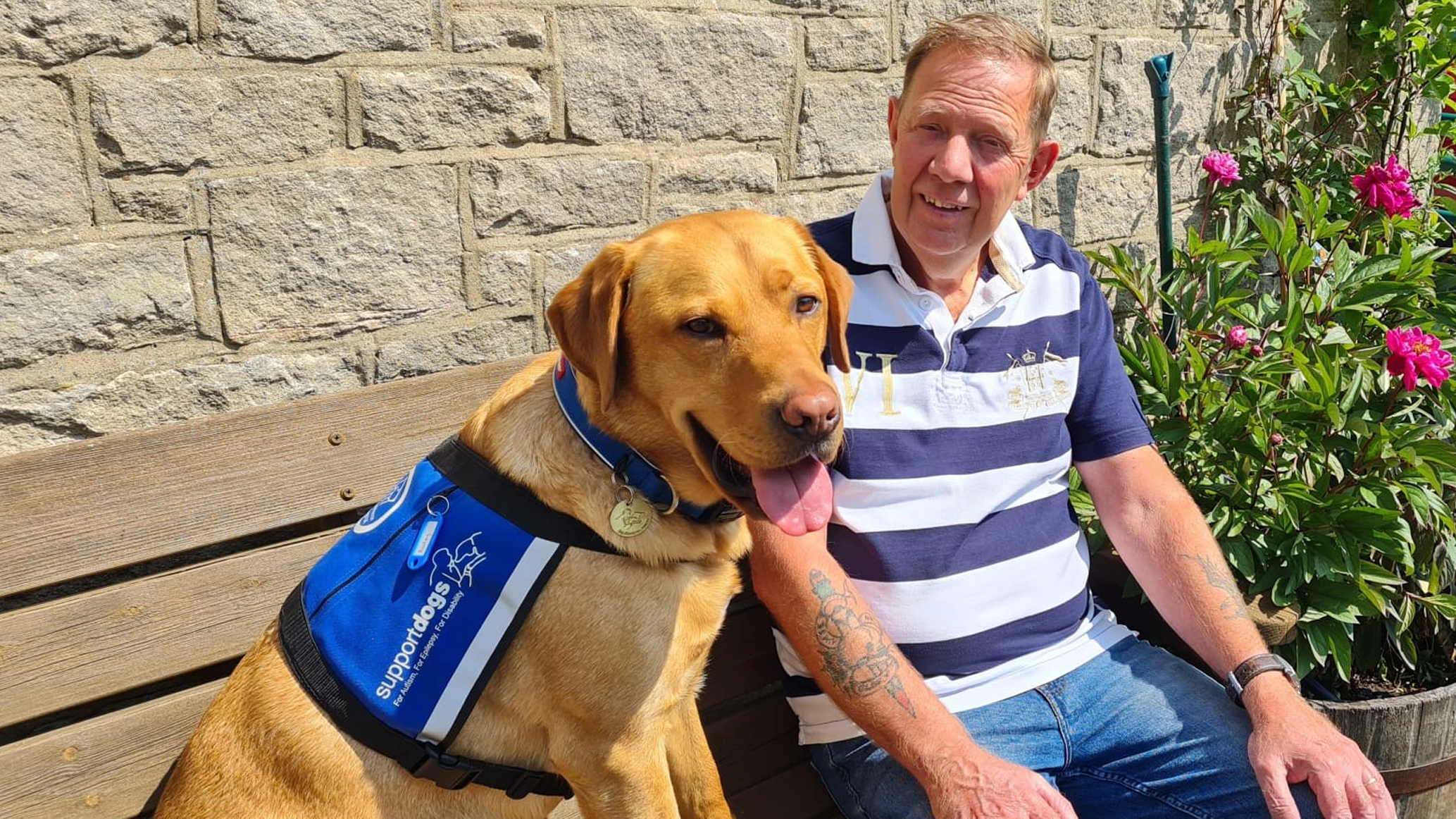 Stephen and Bailey sat on a bench smiling at the camera 