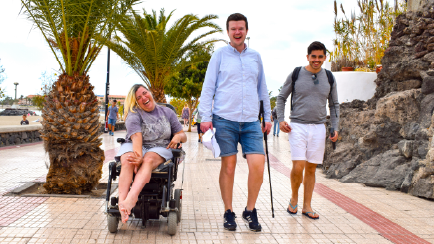 Three people side-by-side. One is in a wheelchair and another has a walking stick