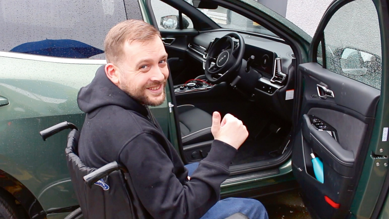 thumbs-up-from-a-male-wheelchair-user-as-he-prepares-to-transfer-to-his-open-car.webp