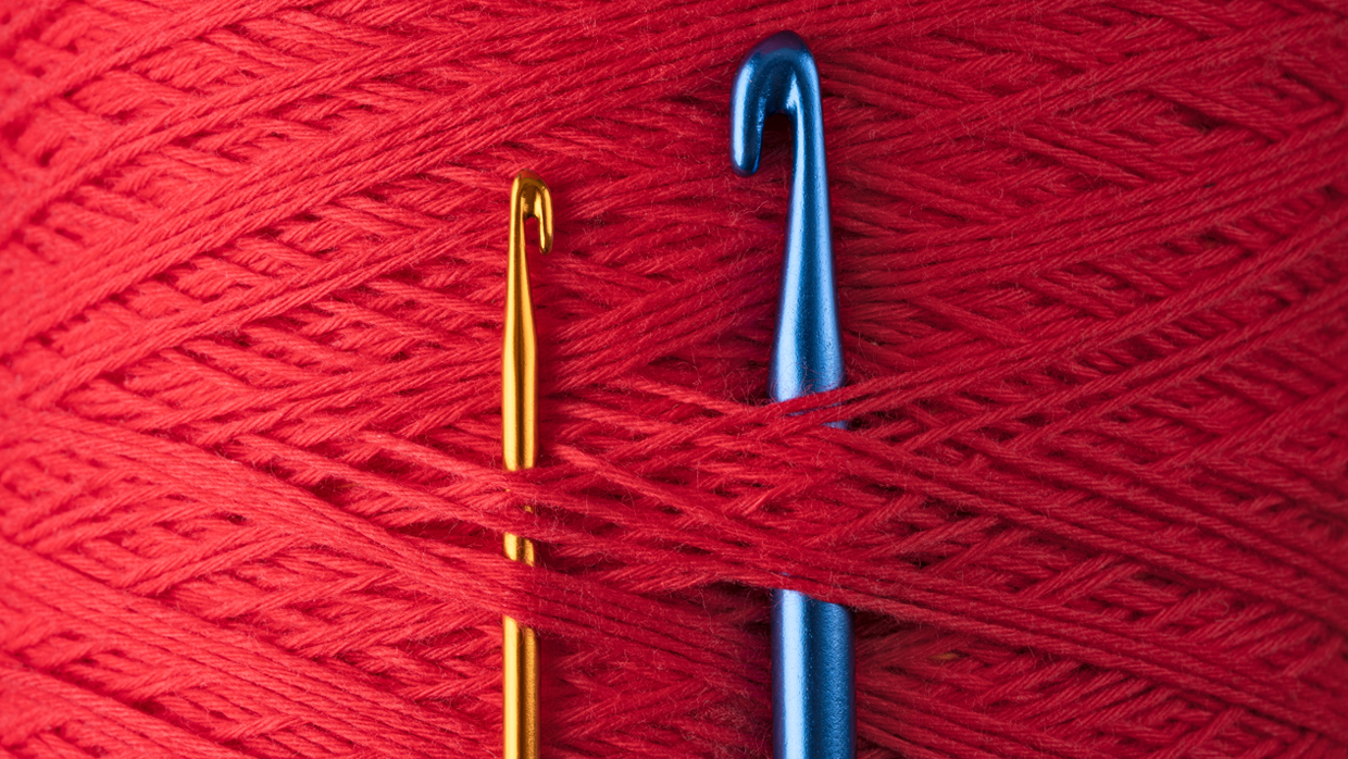 two crochet hooks placed atop a large batch of red wool.jpg